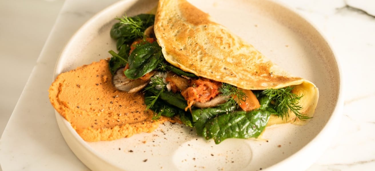 A freshly cooked omelette garnished with herbs, served on a white plate